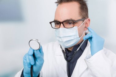 Steteskopla kliniğin önünde duran erkek doktor.