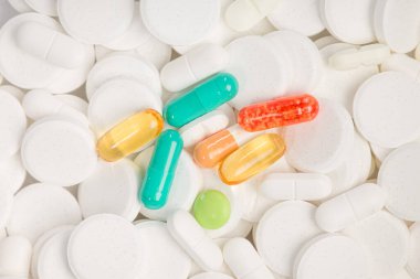 Bir sürü beyaz hap arasında renkli haplar var.