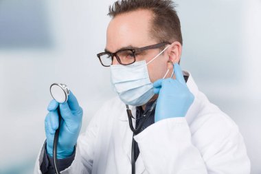 Steteskopla kliniğin önünde duran erkek doktor.