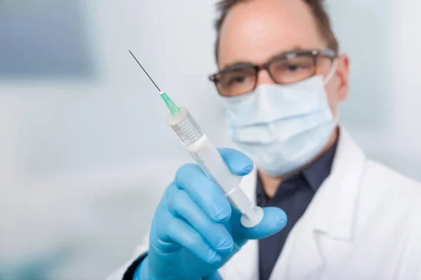 male doctor with medical face mask in front of a clinic room han