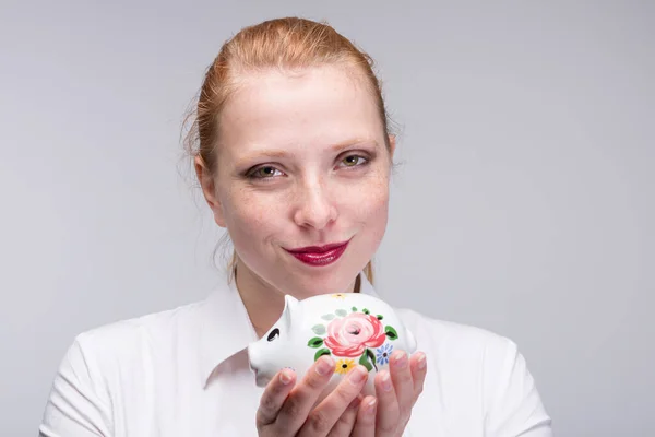 若い赤い髪の女性が貯金箱にコインを入れる ポルセラ — ストック写真