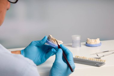 Diş laboratuarında diş boyama teknisyeninin kapağını kapat.