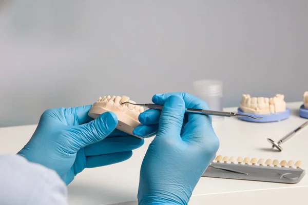 close up of dental technician working on tooth crown in dental laboratory