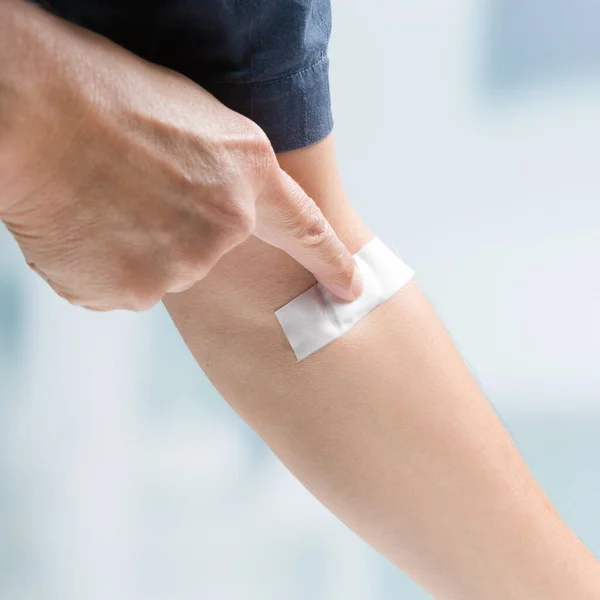 man\'s finger pressing on adhesive tape after taking of a blood sample