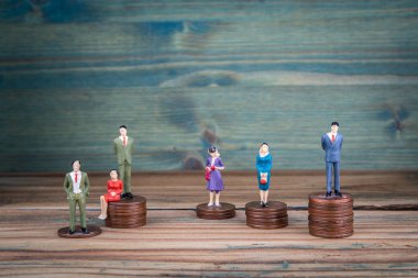 Madeni para yığınlarının üzerinde duran minyatür insanlar.