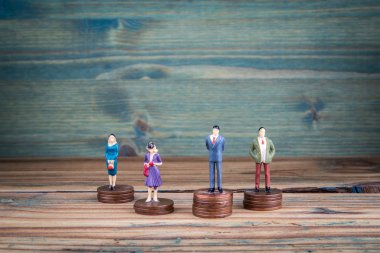 Madeni para yığınlarının üzerinde duran minyatür insanlar.
