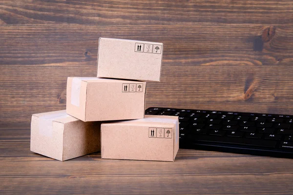 Paper boxes and computer keyboard on wooden background