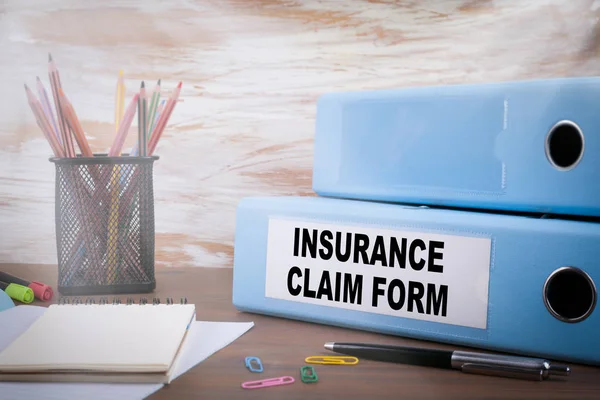 Insurance Claim Form, Office Binder on Wooden Desk