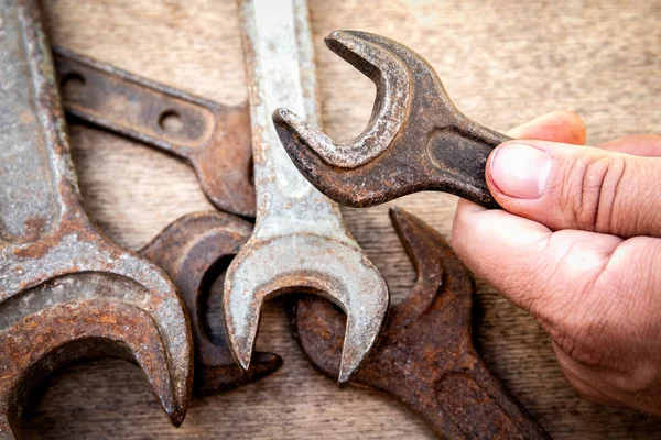 Alter und rostiger Schraubenschlüssel in der Hand auf Holzgrund — Stockfoto