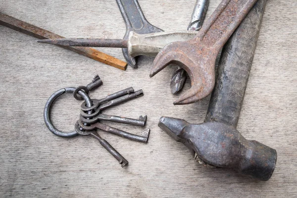 Bündel verschiedener Schlüssel und Handwerkzeuge auf Holzbrett — Stockfoto