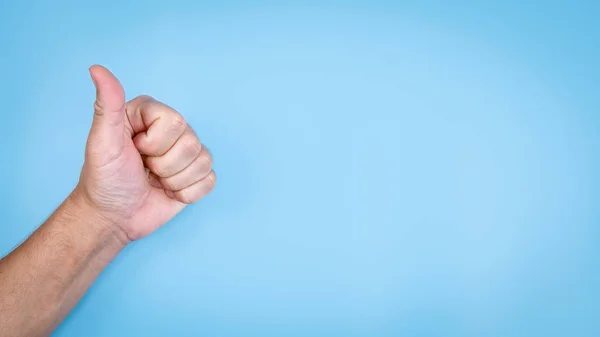 Person showing thumbs up hand gesture on empty blue  background — Stock Photo, Image