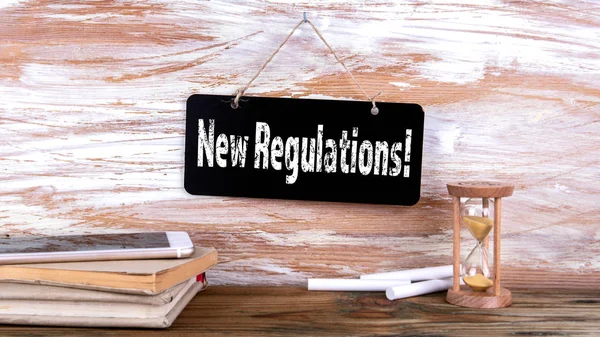 New Regulations. Mobile phone, books and hourglass