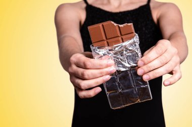 El ele tutuşan çikolatanın yakın çekimi. Diyet, sağlık ve tatlılar