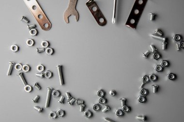 Metal cıvatalar ve fındıklar kopyalama alanı olan gri bir arkaplanda