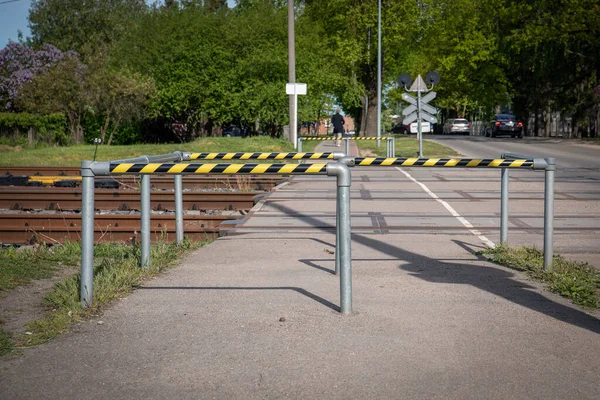 Cruce peatonal a través de líneas ferroviarias. Barreras de seguridad y cintas de advertencia. Medio ambiente urbano — Foto de Stock