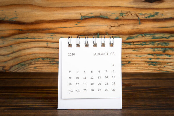 2020 AUGUST. White paper calendar on a wooden table. Time planning