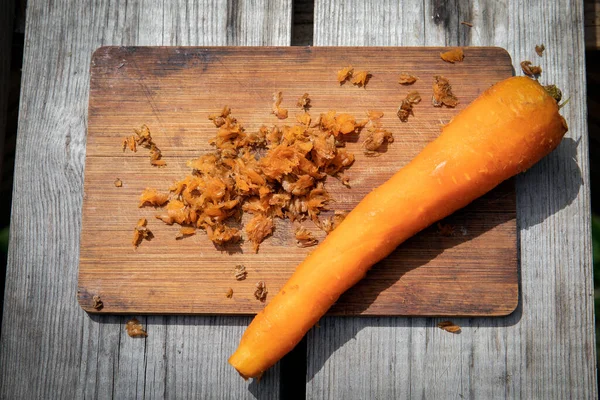 Obierana marchewka na drewnianym kiju. Przygotowanie do gotowania warzyw — Zdjęcie stockowe