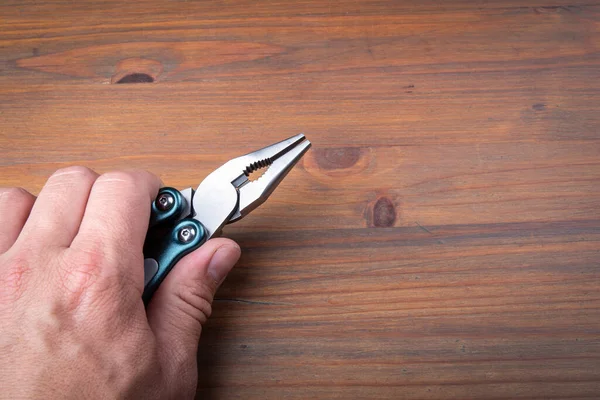 Zange in der Hand auf Holzgrund. Handwerkzeuge zum Halten von Gegenständen — Stockfoto