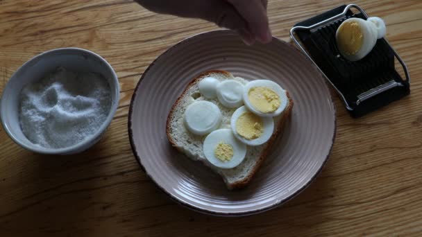 Espolvorear la sal de un tazón pequeño sobre pan blanco con huevos — Vídeos de Stock