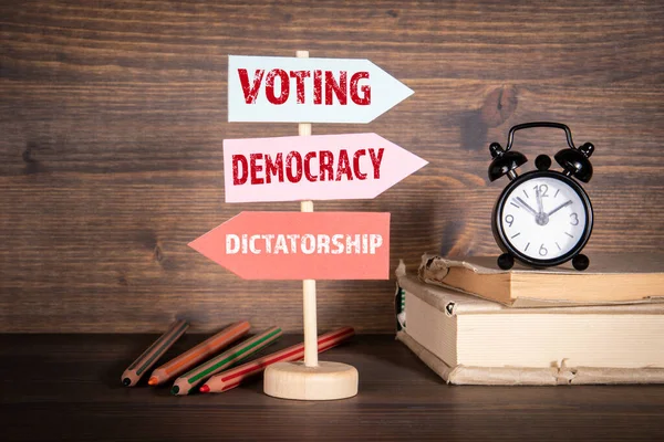 Oy kullanma, demokron ve yarrak sevkiyatı kavramı. Oklu işaret direği. Kitaplar, çalar saat ve kalemler. — Stok fotoğraf