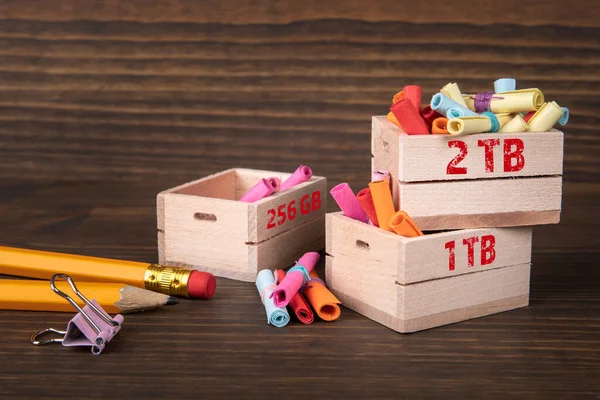 Email, digital memory and server concept. Colored papr scrolls in wooden boxes on dark wooden background.