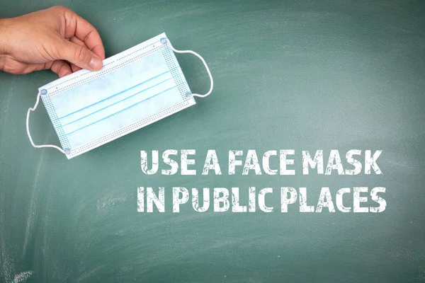 Используйте маску для лица в общественных местах. Зеленая доска — стоковое фото