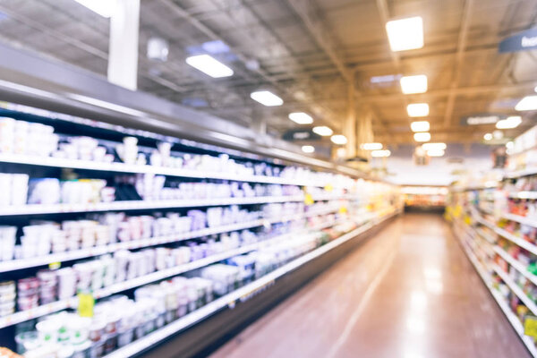 Винтажные размытые полки холодильника с йогуртом в продуктовом магазине.
