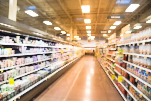 Blurred row of fridge shelves with different brands and flavors of yogurt at local store in Humble, Texas, US.  Variety of yogurt and frozen foods in refrigerator aisle, defocused bokeh light.