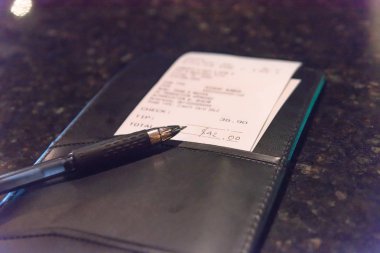 Deri onay yuvasını Restoran bill ve kalem ile açın. Üstten görünüm, yumuşak odak alış irsaliyesiyle mermer çubuğunda veya pub tablo toplam tutar. Müşteri ödeme servis yemek için