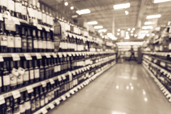 Vintage blurred wine shelves with price tags on display at store in Houston, Texas, US. Defocused rows Wine Liquor bottles on supermarket shelf. Alcoholic beverage abstract with customer shopping