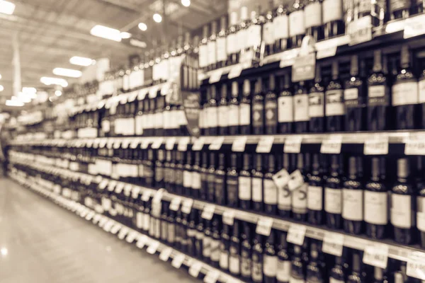 Vintage blurred wine shelves with price tags on display at store in Houston, Texas, US. Defocused rows Wine Liquor bottles on supermarket shelf. Alcoholic beverage abstract with customer shopping