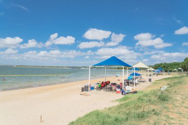 Texas, Usa-Haziran 16, 2018: waterfront Lynn Creek Park, Grand Prairie, Texas, güzel beyaz kum plaj. Yüzme, yüzen, grup kamp ve piknik lakeside çadırlar, bulut mavi gökyüzü, insanlar zevk