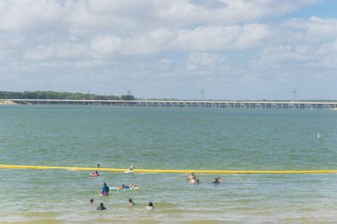 Texas, Usa-Haziran 16, 2018:People yüzme, Lynn Creek Park waterfront adlı yüzen tadını çıkarın. Güvenli yüzme alanı oluşturmak için oluşturmak için göl boyunca sarı şişme şamandıra işaretleri. Güneşli yaz bulut mavi gökyüzü
