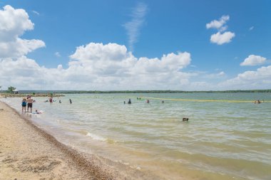 Texas, Usa-Haziran 16, 2018:People yüzme, Lynn Creek Park waterfront adlı yüzen tadını çıkarın. Güvenli yüzme alanı oluşturmak için oluşturmak için göl boyunca sarı şişme şamandıra işaretleri. Güneşli yaz bulut mavi gökyüzü