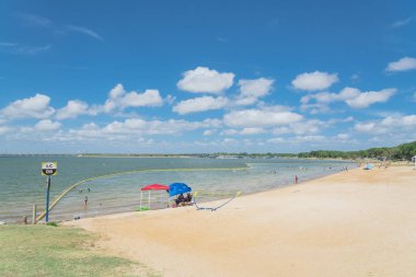 Texas, Usa-Haziran 16, 2018: waterfront Lynn Creek Park, Grand Prairie, Texas, güzel beyaz kum plaj. Yüzme, yüzen, grup kamp ve piknik lakeside çadırlar, bulut mavi gökyüzü, insanlar zevk