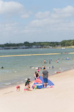 Lakeside beyaz kum Plajı'nda hareket açık hava etkinlikleri güneşli günlerde bulanık. Aile üyeleri çadır, arka planda yüzme insanlar kurma. Waterfront Lynn Creek Park, Grand Prairie, Teksas, ABD