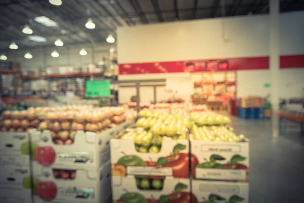 Vintage blurred image organic boxes of fresh fruits on display next to fresh produces at wholesale store in Humble, Texas, US. Defocused supermarket, grocery with customers shopping, bokeh light