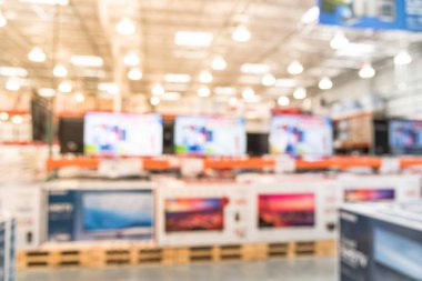 Electronic department store with bokeh blurred background. Television retail shop, TVs display on shelf at wholesale store. Defocused warehouse interior technology aisle and shelves. Business concept. clipart