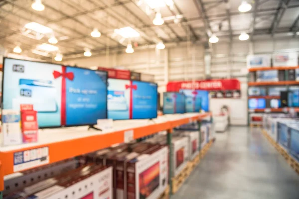 Electronic department store with row of TVs on shelves display. Television retail shop, TVs shelf wholesale store. Defocused warehouse interior technology aisle, inventory, export, business concept.