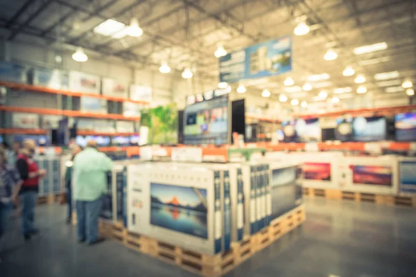 Vintage blurred electronic department store with customer shopping. Television retail shop, TVs display on shelf at wholesale store. Defocused warehouse interior technology aisle, shelves