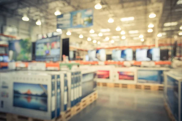 Vintage blurred electronic department store with row of TVs on shelves display. Television retail shop, TVs shelf wholesale store. Defocused warehouse interior technology aisle, inventory concept