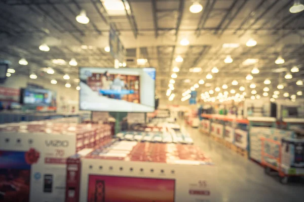 Vintage blurred electronic department store bokeh blurred background. Television retail shop, TVs display on shelf at wholesale store. Defocused warehouse interior technology aisle and shelves