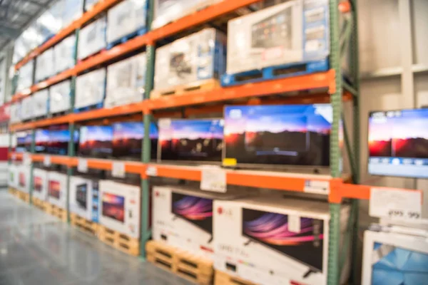 Electronic department store with row of TVs and boxes on shelves display from floor to ceiling. Television retail shop, TVs shelf wholesale store. Defocused warehouse interior technology aisle.