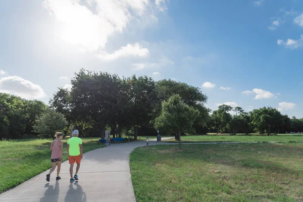 Aktif çift Park'ta sabahın erken saatlerinde koşu görünümünü arka. Yol üzerinde egzersiz insanlar. Sağlıklı yaşam konsepti
