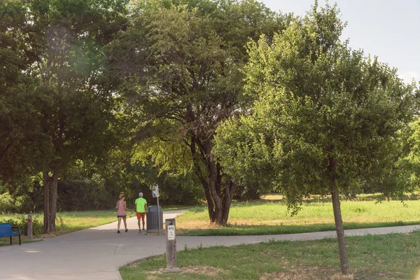 Aktif çift Park'ta sabahın erken saatlerinde koşu görünümünü arka. Yol üzerinde egzersiz insanlar. Sağlıklı yaşam konsepti