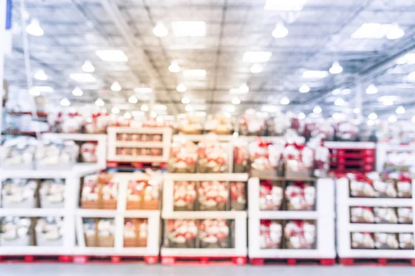 Vintage blurred row of Christmas hamper baskets in wholesale store. Holiday gift baskets with chocolate Santa, cookies, wine, tea. Defocused background interior warehouse, business concept