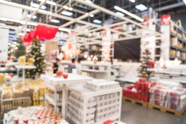 Plastik Noel çan süsleme, bulanık renkli raflarında çelenk, aydınlatma ve suni Noel ağacı süsle satışında büyük mobilya mağazası. Bokeh açık renkli. Müşteri alışveriş