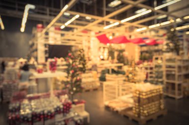 Plastik Noel çan süsleme, bulanık renkli raflarında çelenk, aydınlatma ve suni Noel ağacı süsle satışında büyük mobilya mağazası. Bokeh açık renkli. Müşteri alışveriş