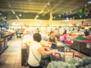 Bulanık müşteri alışveriş için taze sebze, meyve bakkal Texas, Usa. Çeşitli organik ve yerel olarak yetiştirilen ekranda üretir. Süpermarkette sağlıklı gıda arka plan