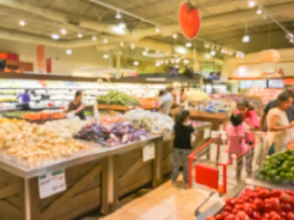 Blurred customer shopping for fresh vegetables, fruits at grocery store in Texas, USA. Variety of organic and locally grown produces on display. Healthy food abstract background in supermarket